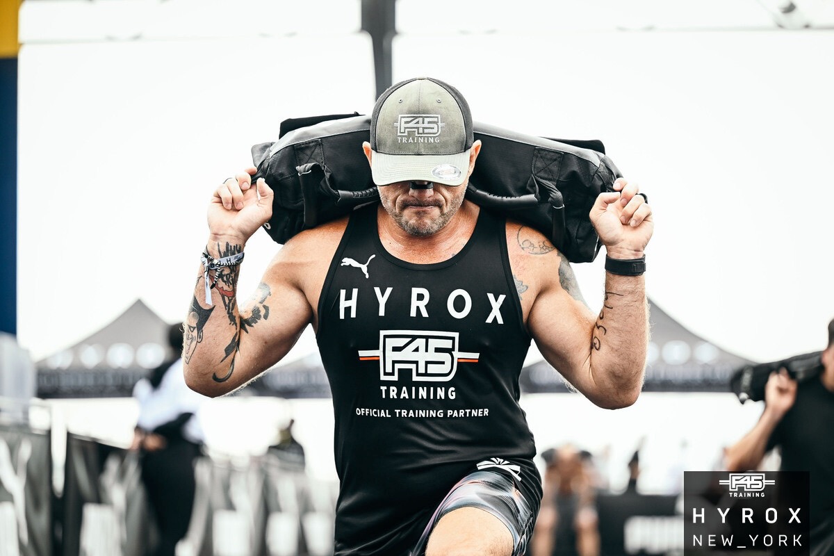 Spencer Thornock carrying a sandbag during a HYROX race